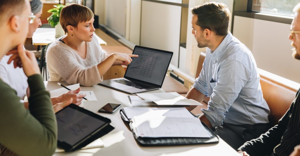 Female Executive Showing Data To Team In Meeting